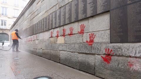 Un employé municipal nettoie le « mur des Justes » couvert de graffitis de mains rouges devant le mémorial de la Shoah à Paris, le 14 mai 2024, après que le monument ait été vandalisé pendant la nuit.