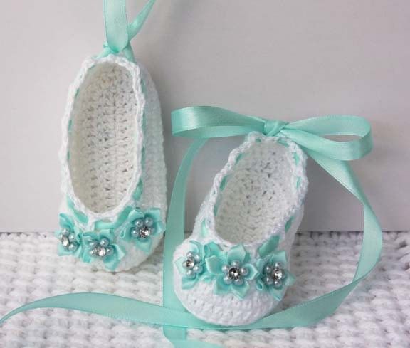 Crochet baby ballerina slippers in white with soft teal accents - Adorned with mini ribbon flowers that have pearls and rhinestone at center - Also embellished with teal satin ribbon that can be laced up baby