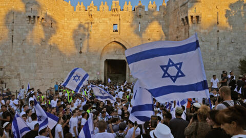 Israelis lift flags during the ultranationalist “March of the Flags” outside Damascus Gate in Jerusalem's Old City on June 15, 2021.