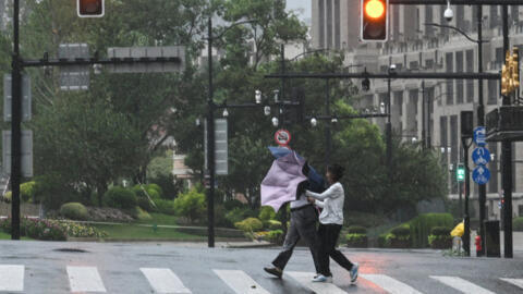 Pedestrians struggle with their umbrellas in strong winds and rain from the passage of Typhoon Bebinca in Shanghai on September 16, 2024. 