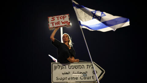 A protester holds a "Stop the War" sign during a protest near the Knesset in Jerusalem, June 17, 2024.