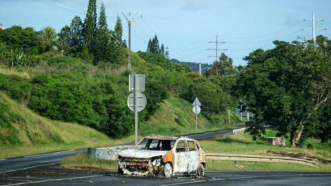 A burnt vehicle is seen on a road leading to the capital in Noumea, France's Pacific territory of New Caledonia, on May 20, 2024.