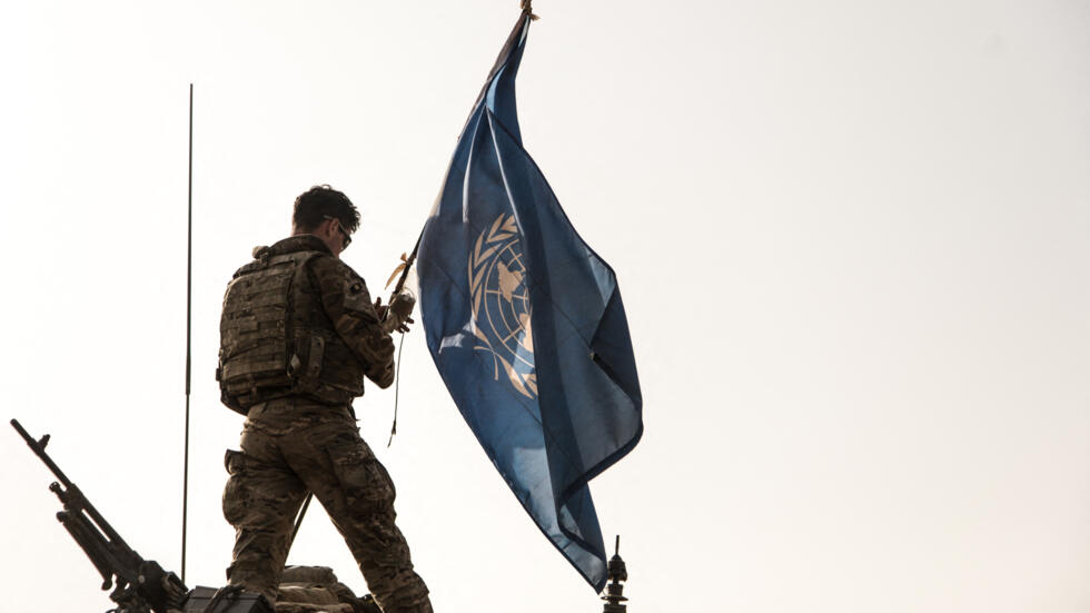 جندي بريطاني من بعثة الأمم المتحدة لحفظ السلام في مالي (مينوسما) يمسك بعلم الأمم المتحدة على سطح مركبة مدرعة خفيفة خلال دورية في ميناكا، مالي، 28 تشرين الأول/أكتوبر 2021.