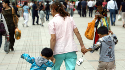 امرأة صينية مع طفليها، 8 مايو، 2007، في بكين.