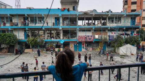 فتاة فلسطينية تنظر نحو فناء مدرسة تابعة للأمم المتحدة تأوي نازحين تعرضت لقصف الإسرائيلي في النصيرات، وسط قطاع غزة، في 6 حزيران/يونيو، 2024.