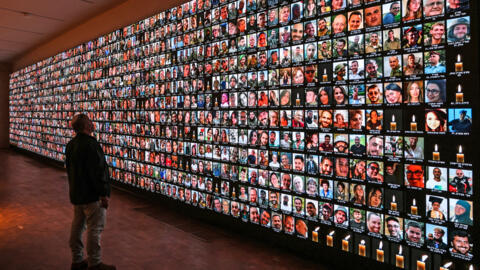 Un homme regarde les portraits des victimes des attaques du 7 octobre, à la Bibliothèque nationale israélienne, à Jérusalem, le 25 janvier 2024.