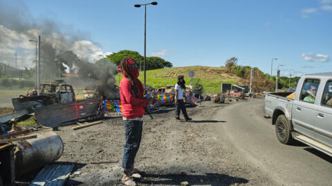 People man a roadblock barricade, with Kanak flags, controlling access to a district in Nouméa, France's Pacific territory of New Caledonia, on May 24, 2024. 