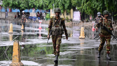 Des soldats bangladais montent la garde près de barricades, dans le cadre d'un couvre-feu instauré à la suite d'affrontements entre police et manifestants, à Dhaka, le 22 juillet 2024.