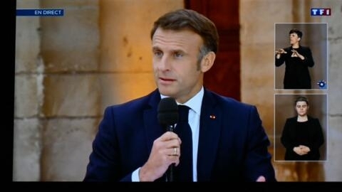 Le président français Emmanuel Macron apparaît sur un écran présentant la chaîne française TF1 alors qu'il s'adresse au public lors d'une interview télévisée à Caen.