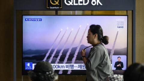 A woman walks past a television screen showing a news broadcast with file footage of a North Korean missile test, at a train station in Seoul on September 18, 2024.