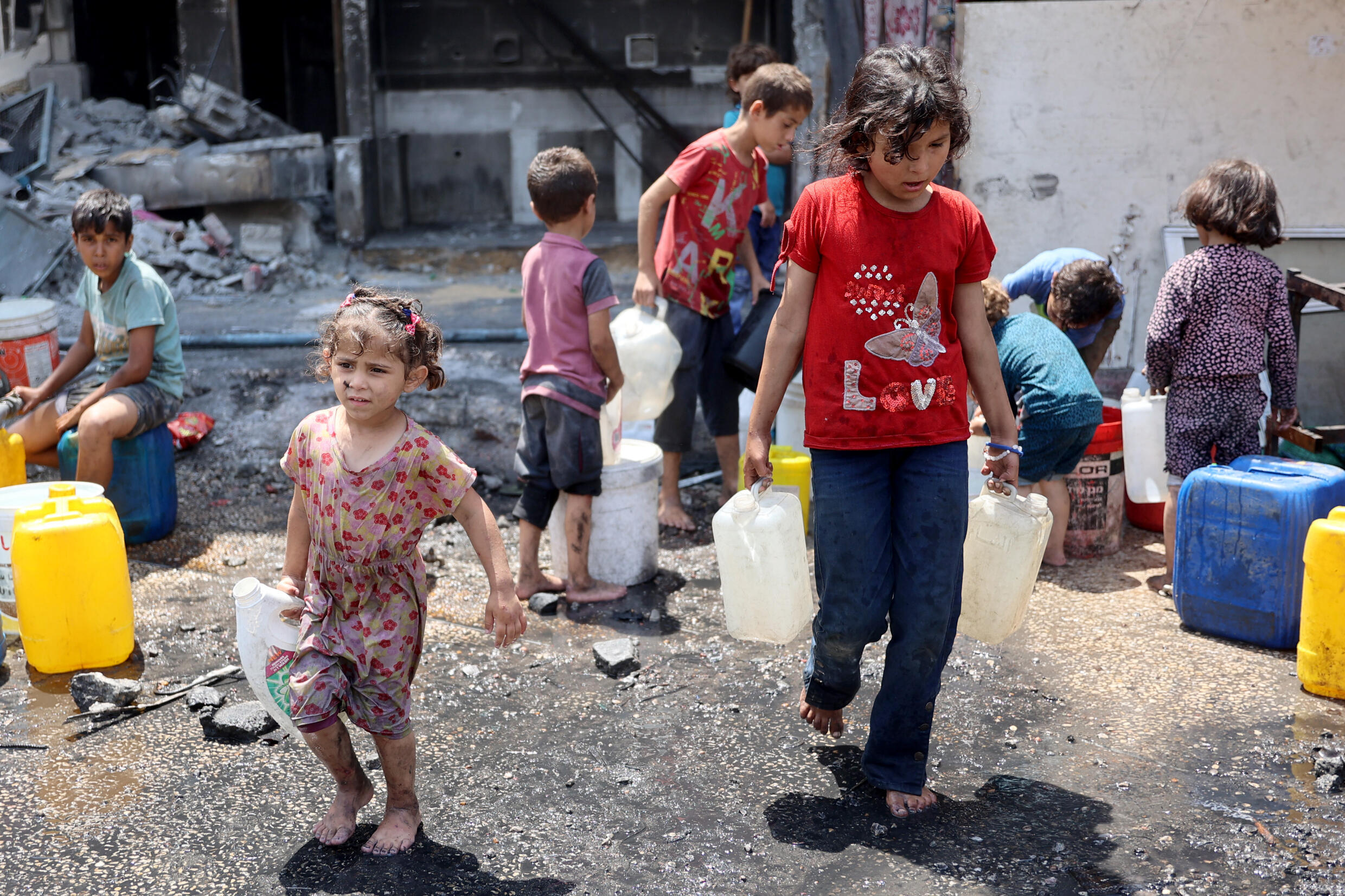 Des enfants remplissent des bidons d'eau dans le camp palestinien en ruines de Jabalia, dans le nord de la bande de Gaza, le 3 juin 2024.