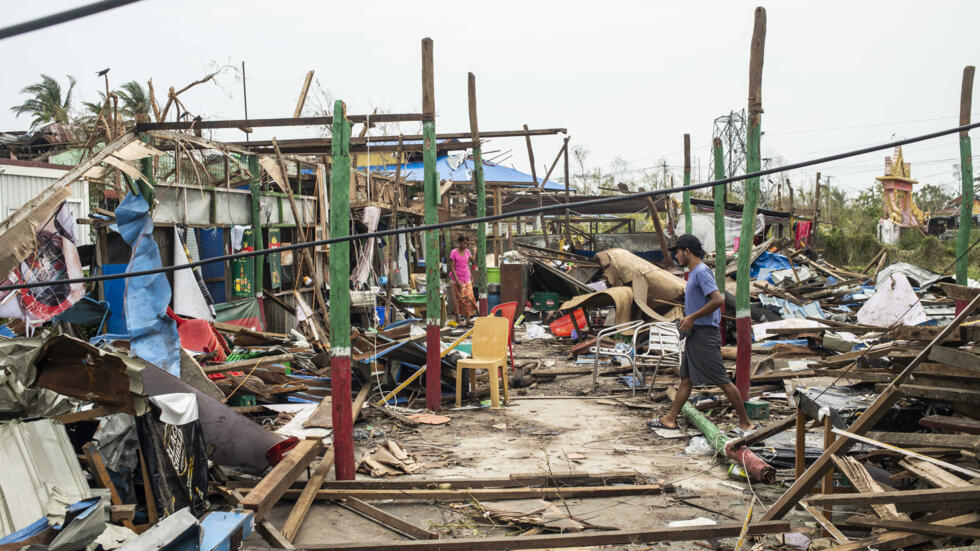 Local residents walk among the ruins of buildings damaged by Cyclone Mocha in Sittwe township, Rakhine State, Myanmar on Tuesday, May 16, 2023. 