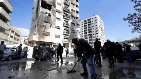 A man sweeps rubble near a residential building after a reported Israeli attack on Syria, according to The Syrian state TV reported that several missiles hit the western neighborhood of Kfar Sousseh d