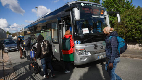 Migrants arrive with their belongings to take a bus to a temporary reception centre, during the clearing of France's biggest squat,  in the southern suburbs of Paris in Vitry-sur-Seine.