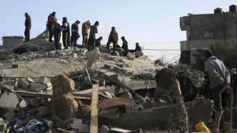 فلسطينيون يقفون فوق أنقاض بناية دمرها قصف إسرائيلي في رفح، جنوب قطاع غزة 3 مارس 2024.
