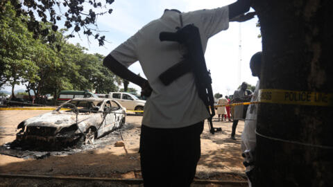 A police officer stands beside a burnt prison vehicle in Abuja, Nigeria on July 6, 2022, after suspected Boko Haram gunmen attacked the Kuje Medium Prison. 