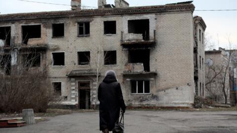 A woman walks past an old destroyed building in small town of Krasnogorivka, Donetsk region on February 22, 2022.