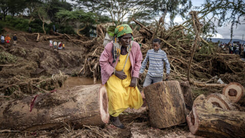 A woman and young child make their way among fallen trees caused by floods and landslides in Mai Mahiu, Kenya on April 30, 2024. 