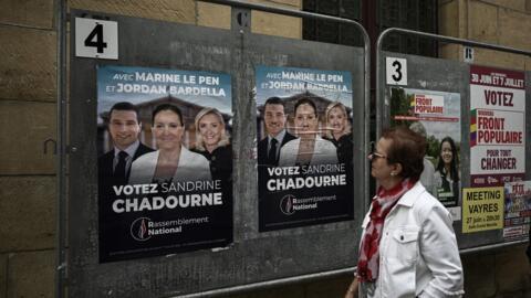 A woman looks at election posters of French far-right Rassemblement National (RN) candidate Sandrine Chadournec (C) in Libourne, southwestern France on July 2, 2024 as part of the French legislative e