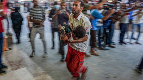 A paramedic carries a child wounded during Israeli bombardment to the emergency ward at Nassr hospital in Khan Yunis, on the southern Gaza Strip on July 9, 2024