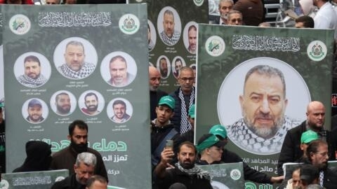 أشخاص يحملون لافتات عليها صور صالح العاروري فيما تجمع مشيعون خلال جنازته في بيروت، لبنان في 4 يناير/يناير الثاني 2024.