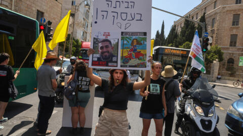 Demonstrators lift placards and chant slogans during an anti-government protest calling for the release of Israelis held hostage by Palestinian militants in Gaza since October, in central Jerusalem on