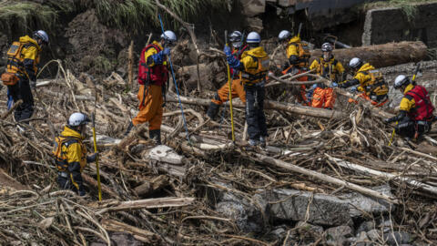 Rescue personnel search for missing people in debris washed away from flooding by the Tsukada river following heavy rain in Wajima city, Ishikawa prefecture on September 23, 2024.