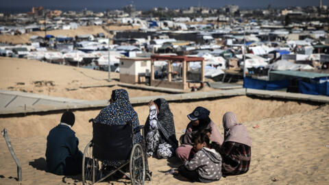 Displaced Palestinian women and gather on a sand dune above a makeshift camp on the Egyptian border, west of Rafah in the southern Gaza Strip on January 14, 2024, as the ongoing war between Israel and