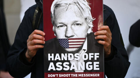 Un soutien du lanceur d'alerte Julian Assange avec une affiche, le 20 avril 2022 devant le tribunal de première instance de Westminster, à Londres (Royaume-Uni).