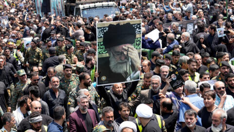 Mourners carry a portrait of Iran's supreme leader, Ayatollah Ali Khamenei, during the funeral procession of Iran's President Ebrahim Raisi through Tehran on May 22, 2024.