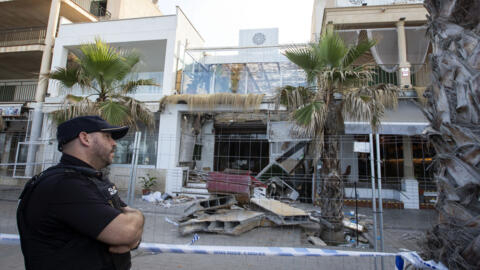 Un officier de police se tient devant l'immeuble qui s'est effondré jeudi à Playa de Palma, sur l'île de Majorque, en Espagne le 24 mai 2024, faisant quatre morts et 16 blessés. 