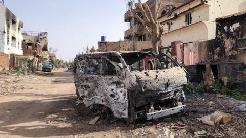 Véhicule brûlé devant un magasin endommagé à Omdourman, le 30 mai 2024.