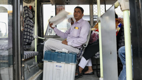 Un agent électoral transportant une machine pour voter utilise un tissu pour se rafraîchir alors qu'il attend à l'intérieur d'un bus dans la ville de Varanasi, le 31 mai 2024.