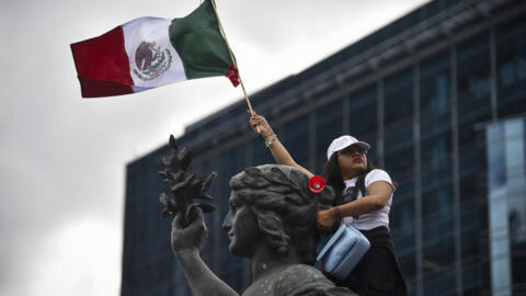 A member of the National Association of Magistrates and District Judges holds a Mexican flag as she takes part in a protest.