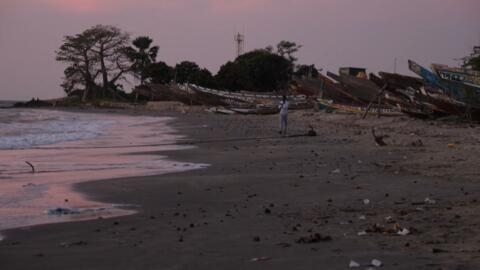 Un homme marchant sur une plage, à Barra, le 5 décembre 2019, après qu'au moins 62 personnes sont mortes lorsque leur embarcation a chaviré au large des côtes mauritaniennes.