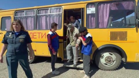 This video grab taken from a handout footage released by the Russian authorities of the Russian southwestern region of Krasnodar, shows volunteers helping evacuees alight from an evacuation bus from a