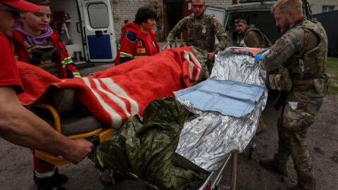 Militares e médicos atendem soldados feridos em Vovchansk, neste domingo (12/05/24).