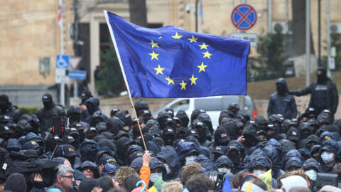Manifestante segura uma bandeira da União Europeia diante de policiais em manifestação para protestar contra projeto de lei sobre “influência estrangeira” em Tbilisi, Geórgia, em 14 de maio de 2024. 