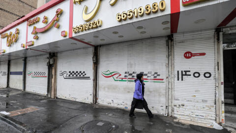Uma mulher passa diante de lojas fechadas devido à greve na rua Satarkhan, em Teerã, em 5 de dezembro de 2022.