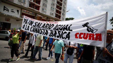 Professores e funcionários públicos seguram um cartaz com os dizeres "Por um salário igual à Cesta Básica", enquanto participam de um protesto para exigir melhores salários, antes do início do novo ano letivo, em Caracas, Venezuela, em 18 de setembro de 2023.