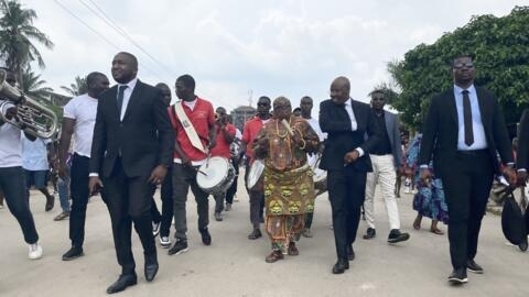 Asalfo (au centre, en costume), le leader du groupe de musique ivoirien Magic System, en visite dans son quartier d'Anoumabo.