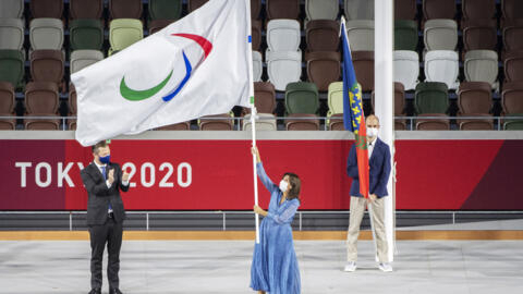Andrew Parsons (L), president of the International Paralympic Committee (IPC), looks at Anne Hidalgo, mayor of Paris, waving the Paralympic Games flag during the closing ceremony of the Tokyo 2020 Par