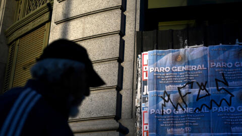 Um homem passa por uma placa sobre a greve geral em Buenos Aires em 9 de maio de 2024.