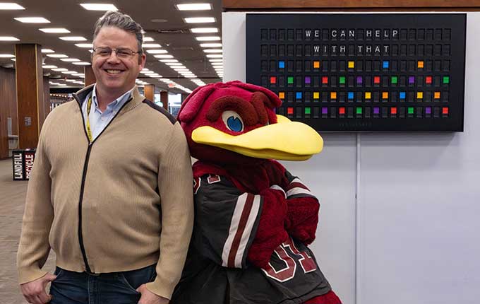 Cocky and a librarian standing in front of a board that says 