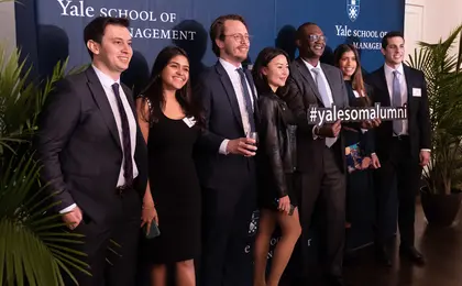 Alumni standing in front of blue backdrop