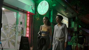 Turisti passano davanti a un negozio di cannabis appena legalizzato, il 10 agosto 2022, a Bangkok, in Thailandia. 