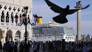 In questa foto di archivio, una nave da crociera passa davanti a Piazza San Marco piena di turisti, a Venezia, Italia