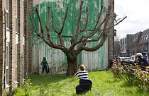 Des personnes regardent une nouvelle peinture de Banksy sur un mur à Londres, lundi 18 mars 2024. 