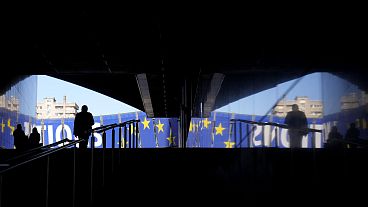 Ein Mann geht am Montag, den 29. April 2024, auf ein Wahlbanner vor dem Europäischen Parlament in Brüssel zu. Die Europawahlen finden vom 6. bis 9. Juni 2024 statt.