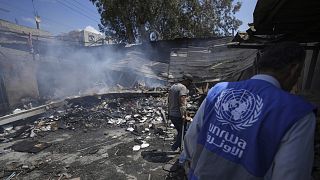 Ciudadanos palestinos observan la destrucción tras un ataque israelí a una escuela gestionada por la UNRWA en la Franja de Gaza, el 14 de mayo de 2024.
